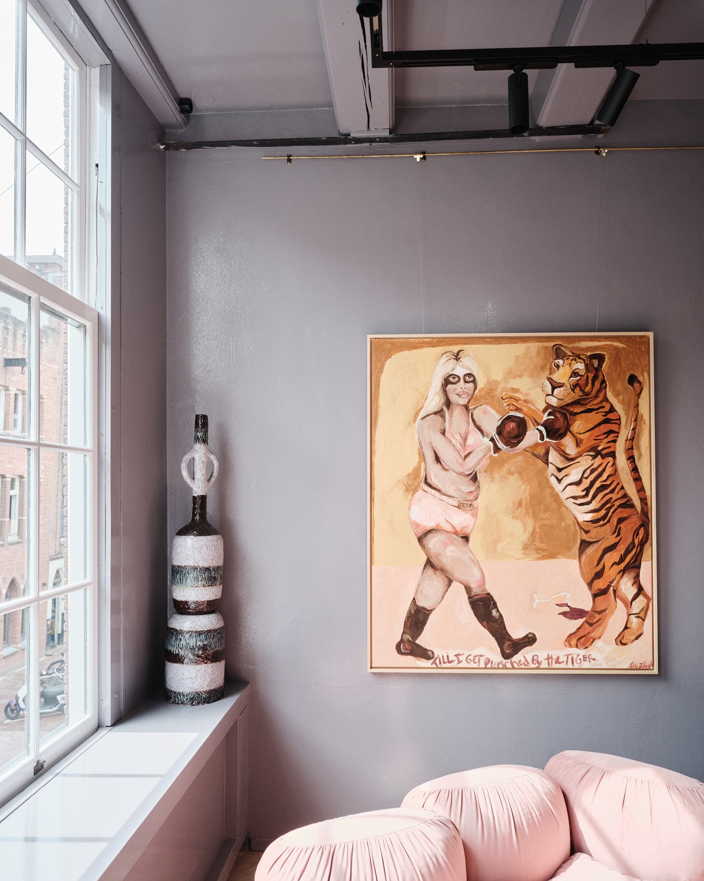 Gallery interior with a painting of a woman boxing a tiger